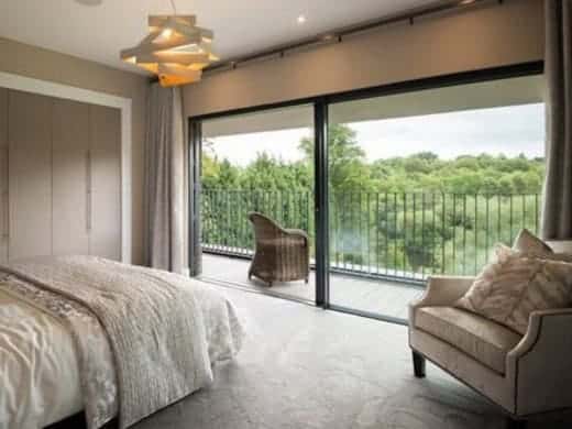 Bedroom with aluminium sliding patio doors leading to the balcony - Wymondham Windows